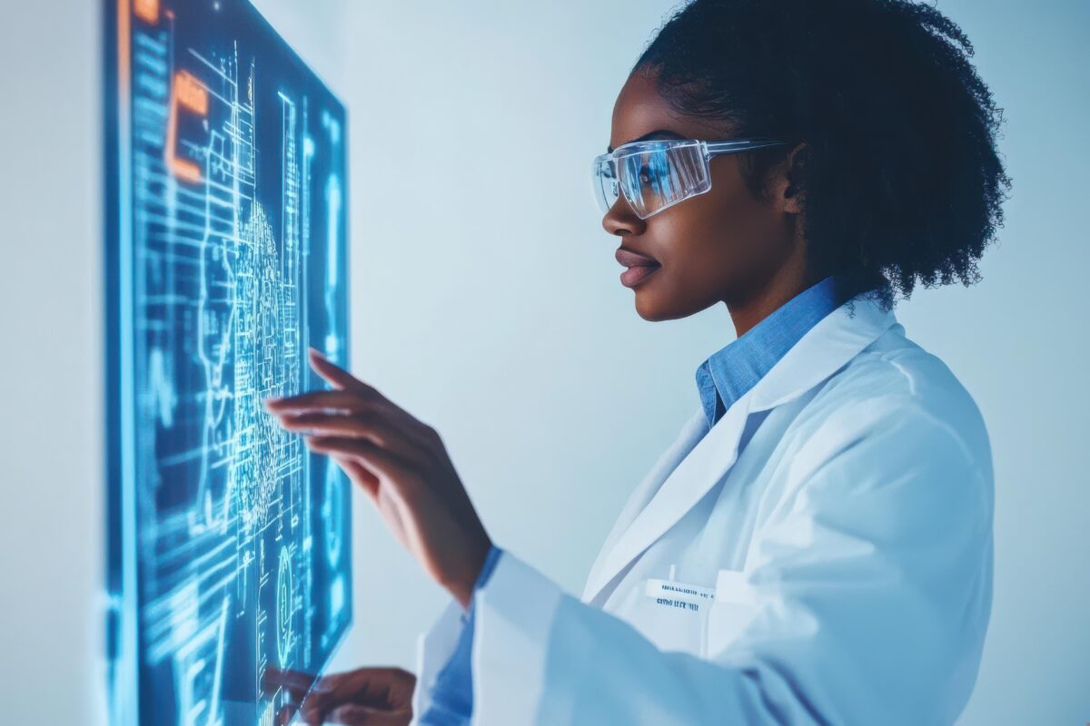 Person in a white lab coat and protective eyewear interacting with a large transparent digital touchscreen display showing blue and orange holographic graphics, circuit patterns, charts, and diagrams in a modern laboratory setting.